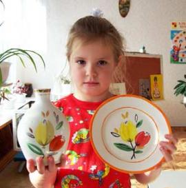 Даше Новоселовой всего 6 лет, но эту тарелочку она расписала сама. В правой руке Даша держит оригинальную вазу, сделанную на заводе